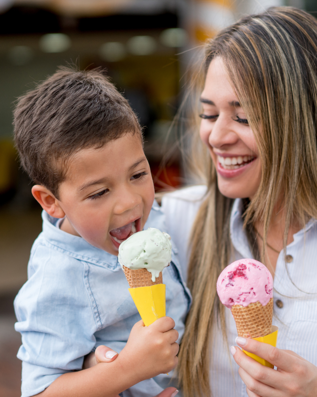 Mother and child enjoying colorful ice cream cones, featuring mint green and pink flavors, highlighting the joy of family moments at Hugs Ice Cream.