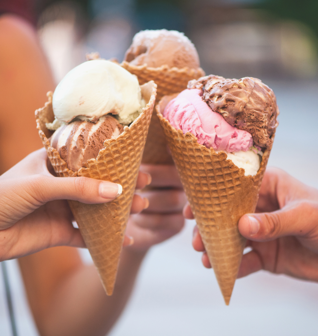 Ice-Cream-Springdale-Ar Hands holding ice cream cones with various flavors, celebrating handcrafted joy from Hugs Ice Cream in Northwest Arkansas.